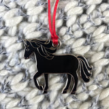 Black horse-shaped pendant on a red cord against a textured white background