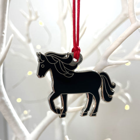 Black horse ornament hanging on a red string against a white branch background
