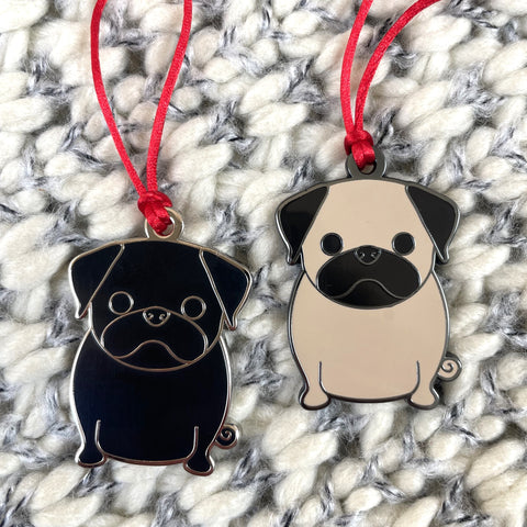 Two pug-shaped keychains on red strings against a textured white and gray background