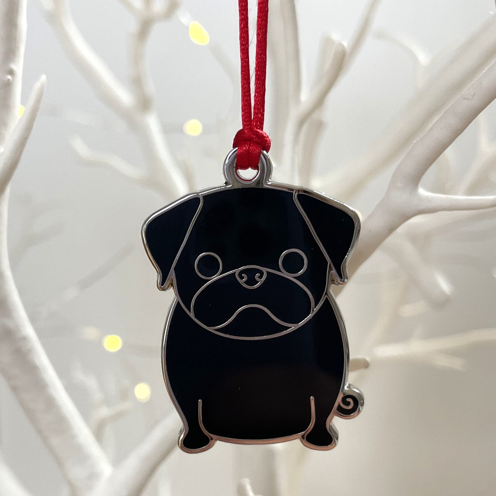 Black pug-shaped pendant on a red string against a white branch background