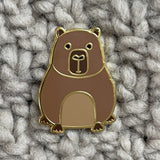 Brown capybara pin on a textured gray fabric background