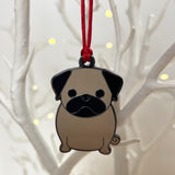 Pug-shaped ornament hanging on a red string against a white branch background with small lights.