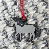 Enamel and metal Horse shaped pendant with a red string on a textured fabric background
