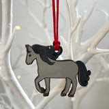 Horse-shaped ornament hanging on a red string against a white branch background