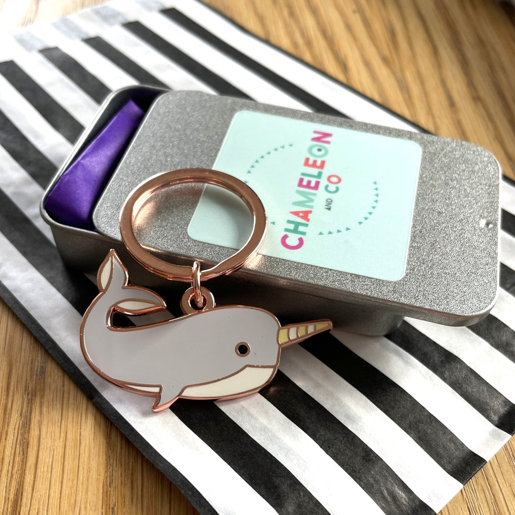 Narwhal keychain in a Chameleon and Co tin on a striped surface