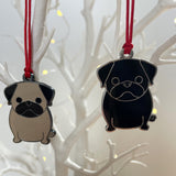 Two pug-shaped ornaments on red strings against a white branch background.