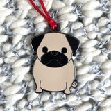 Pug-shaped keychain with a red string on a textured surface